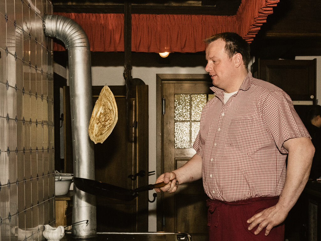 Dieter beim Pfannkuchenwerfen an der Kochmaschine im Fleet vom Bussjans Hof