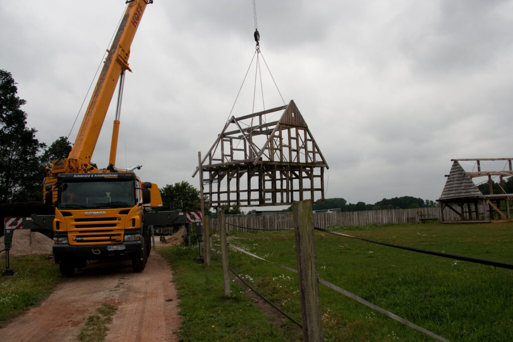 Fachwerk-Konstruktion wird per Kran aufgestellt - Wiederaufbau eines historischen Hauses auf dem Hofgelände.
