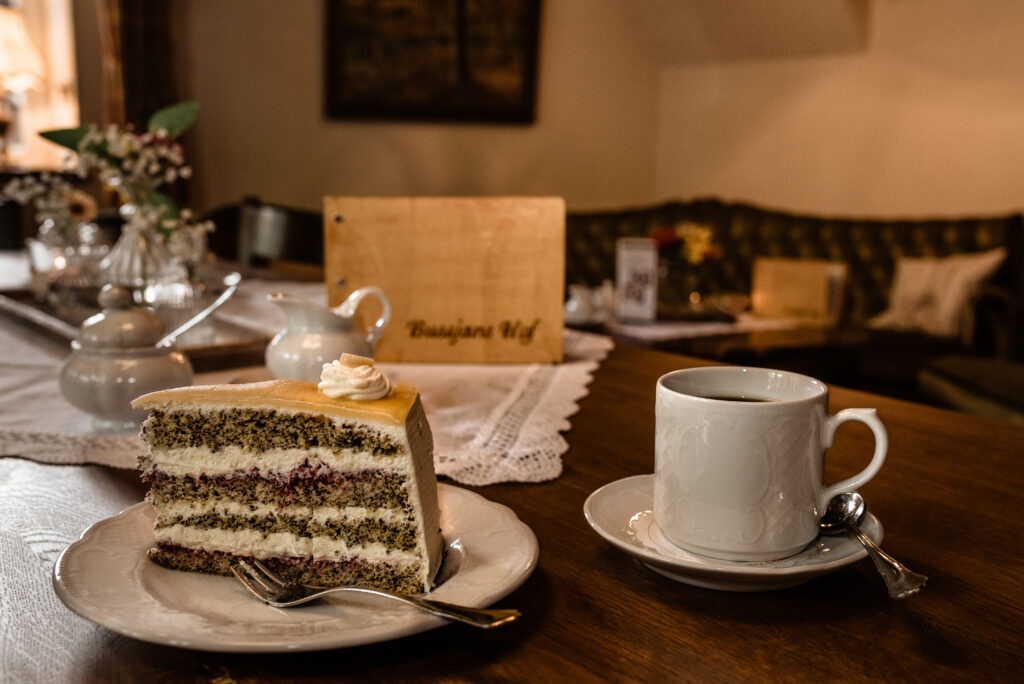 Stück Torte und Kaffeetasse auf Holztisch im gemütlichen Hofcafé von Bussjans Hof.