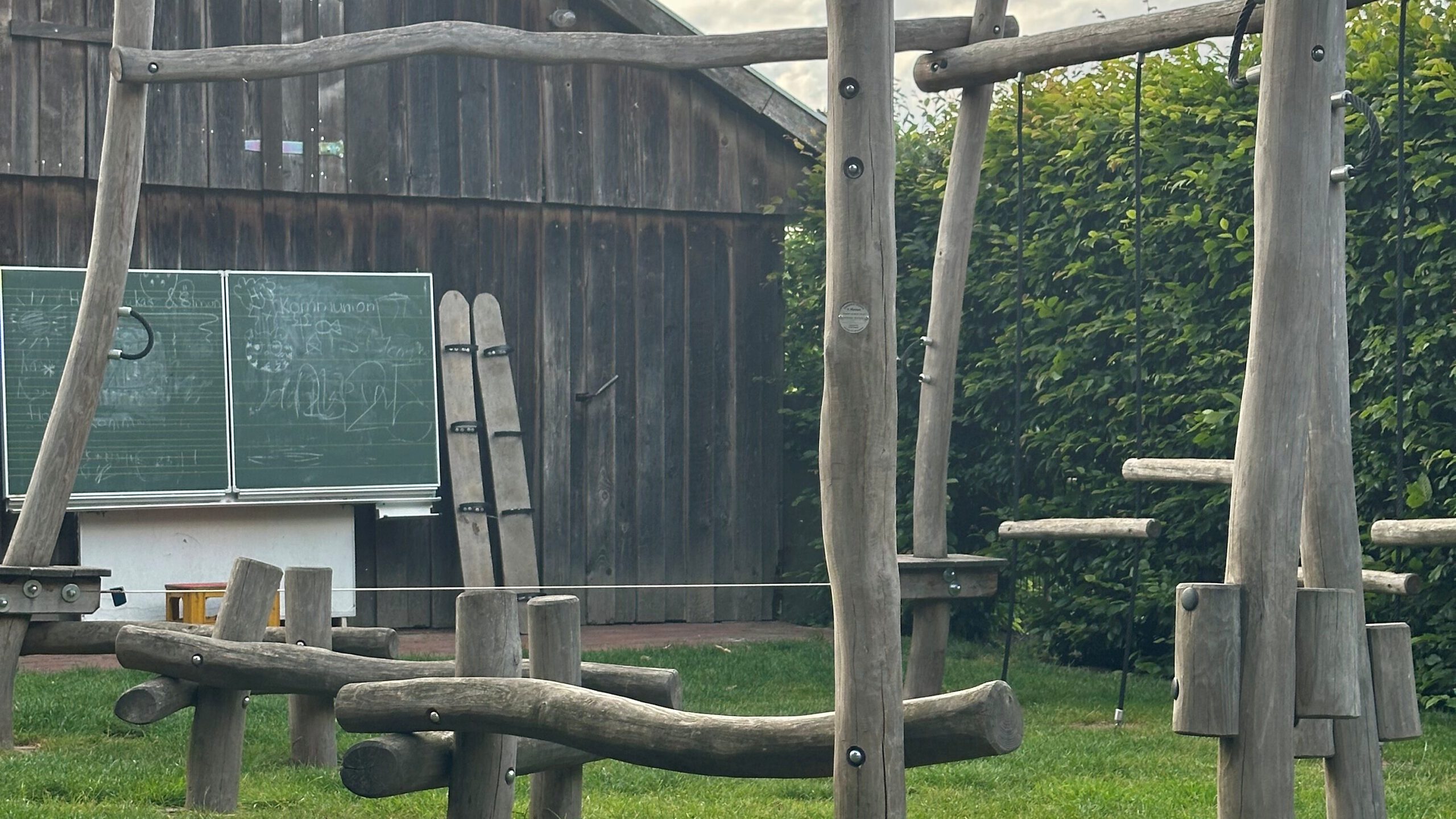 Naturnaher Spielplatz im Holzelemente und Schultafel im Gartenbereich von Bussjans Hof