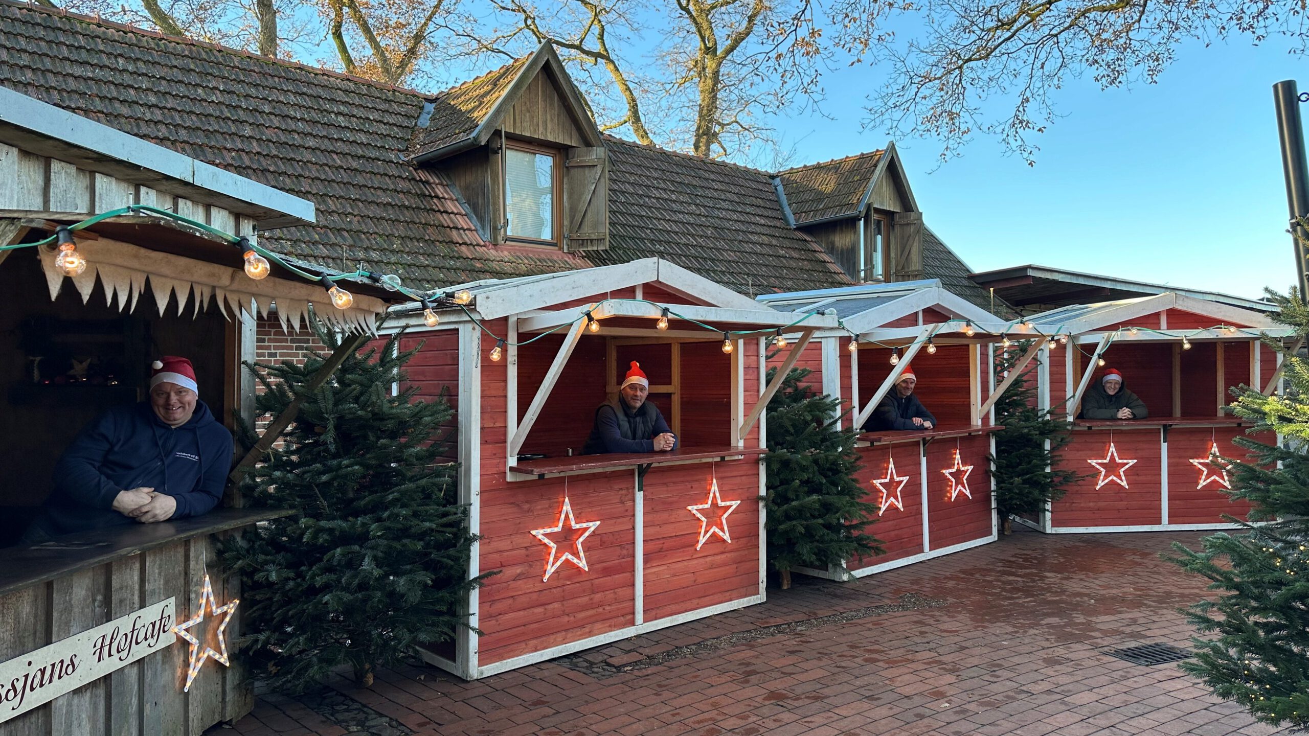 Kleiner Weihnachtsmarkt mit Holzhütten, Tannebäume und Lichterketten auf Bussjans Hof.